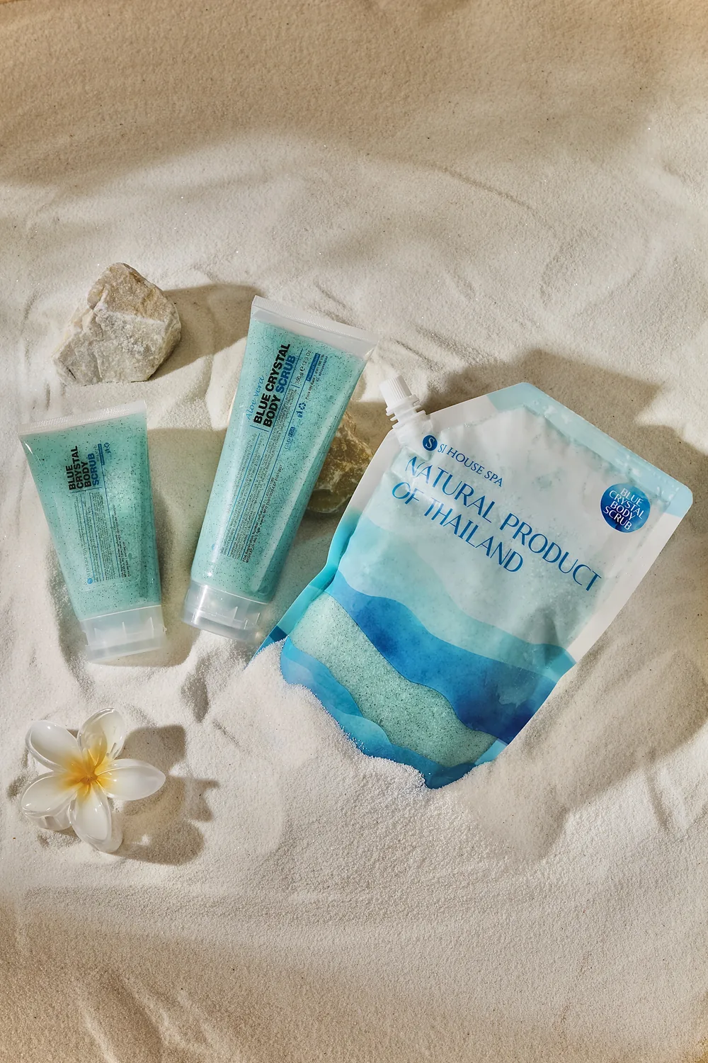 สครับ Blue Crystal และถุงเติมจัดวางบนทรายพร้อมดอกลีลาวดี